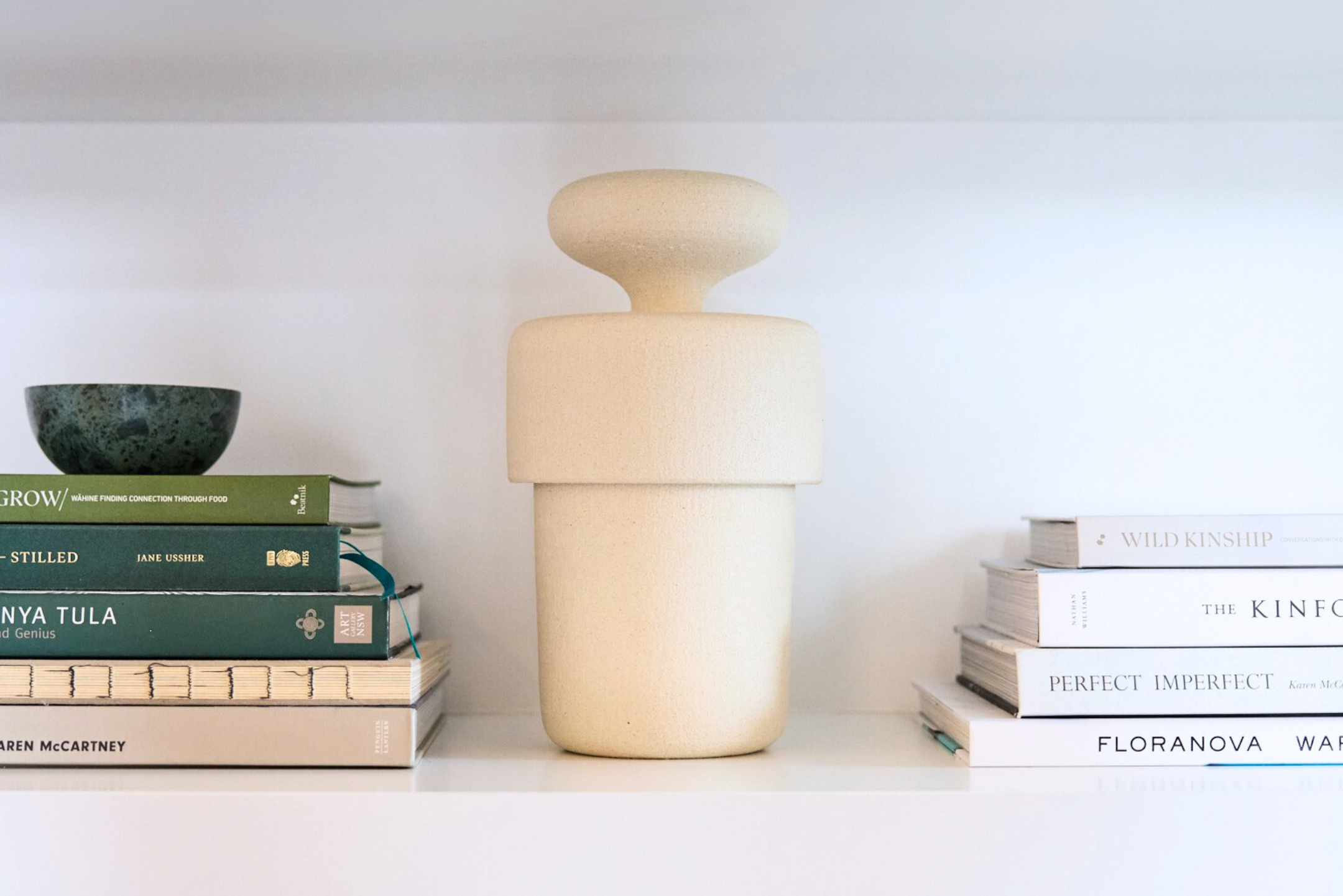 The sculptural Andromeda I cremation urn form Vaso sitting comfortably on display amongst books in a modern home