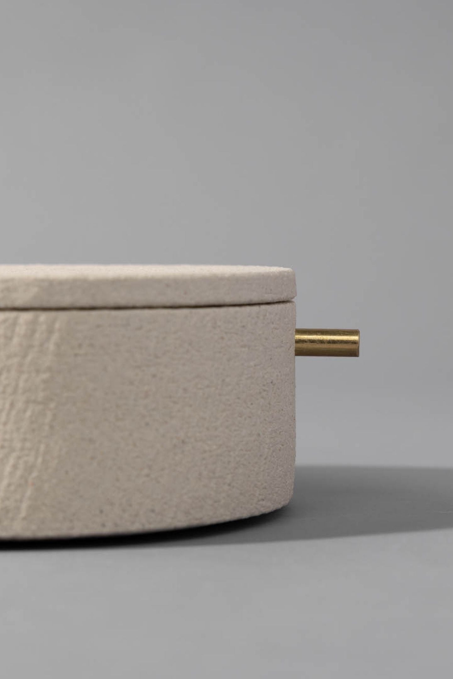 Close up of one of the Memento Bundle of cremation urns in natural clay with brass accent on a grey background.