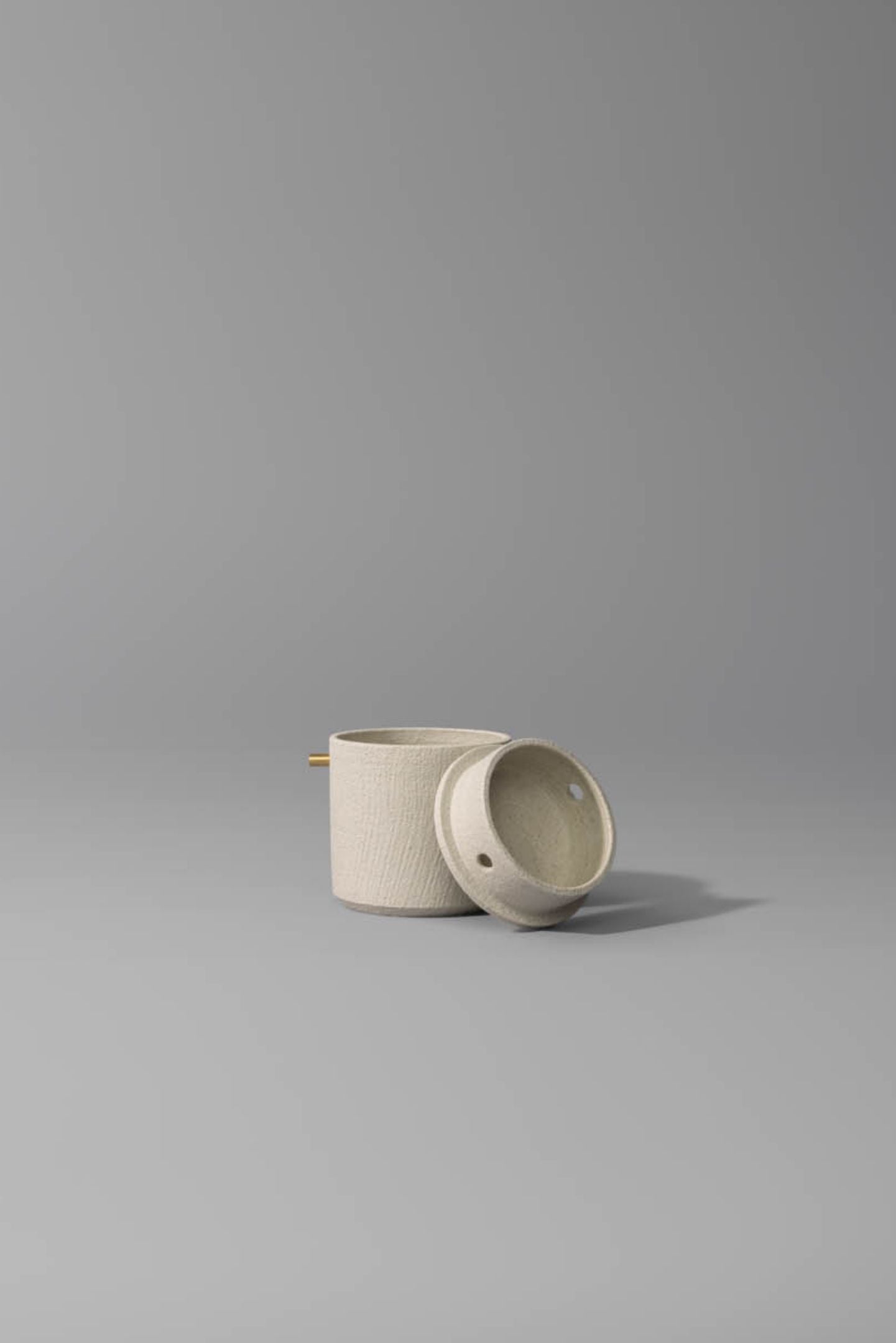 One of the Vaso Memento Bundle of cremation urns featuring a modern ceramic urn with brass accents.