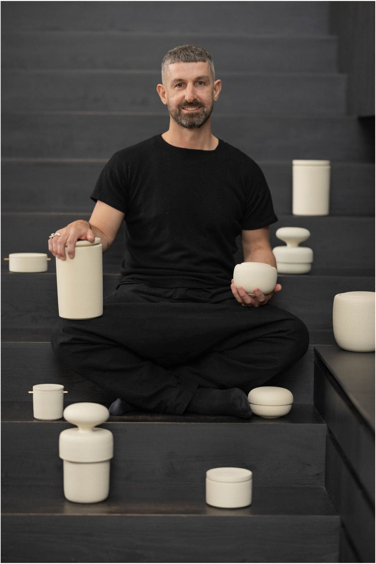 Ceramicist Craig Spencer sitting amongst his handcrafted urns for Vaso